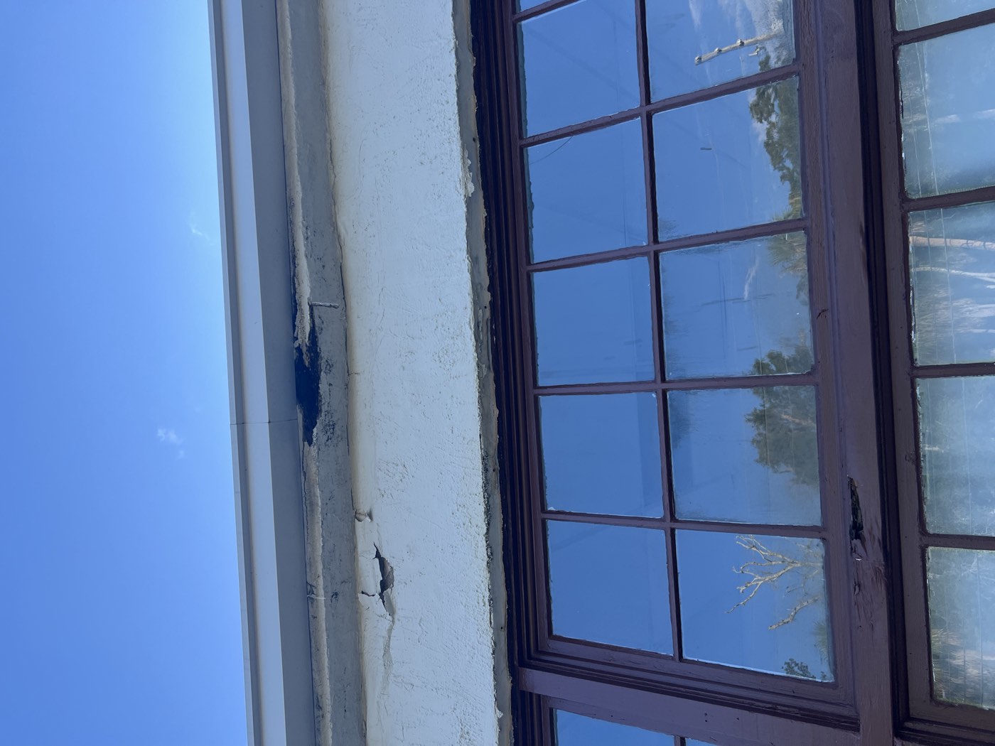 Cracked and crumbling stucco above a storefront window
