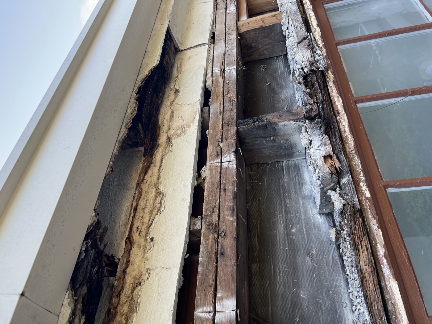 Old stucco removed, exposing rotted wood framing