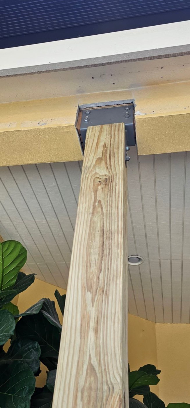 A new wood porch post with a bare, unfinished beam above it